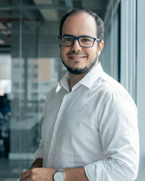Portrait of João Bertacchi in a white shirt and glasses
